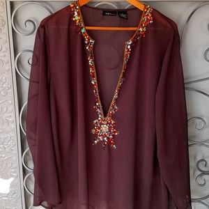 Polyester 100%. With sequin design around neckline and front. NWOT. Lovely top.